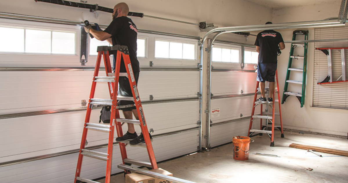 Technicians repairing a garage door.